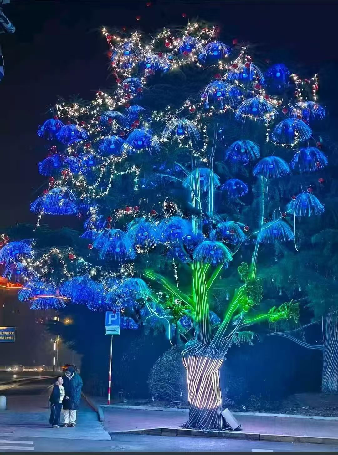 A tree illuminated with blue decorative lights at night